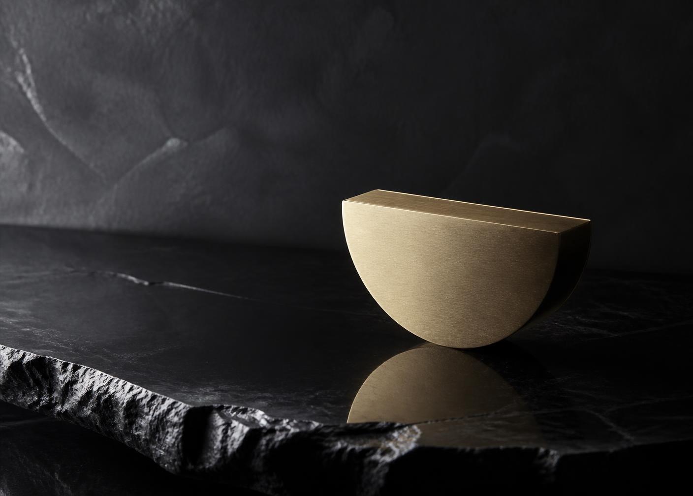 A brushed champagne form resting on polished obsidian stone